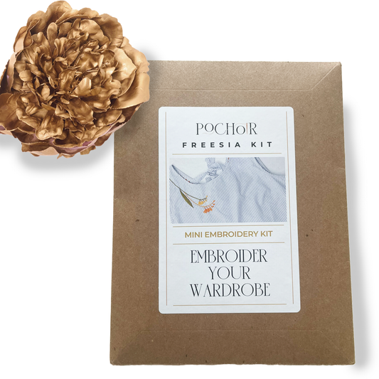 Brown cardboard packaging with a label for the Freesia Mini Embroidery Kit, accompanied by a gold flower on a white background.